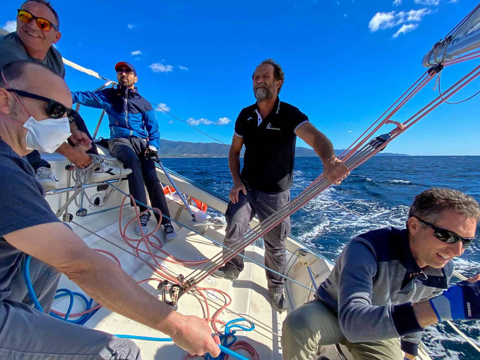 Principianti entusiasti imparano a veleggiare durante lezioni di vela in Sardegna